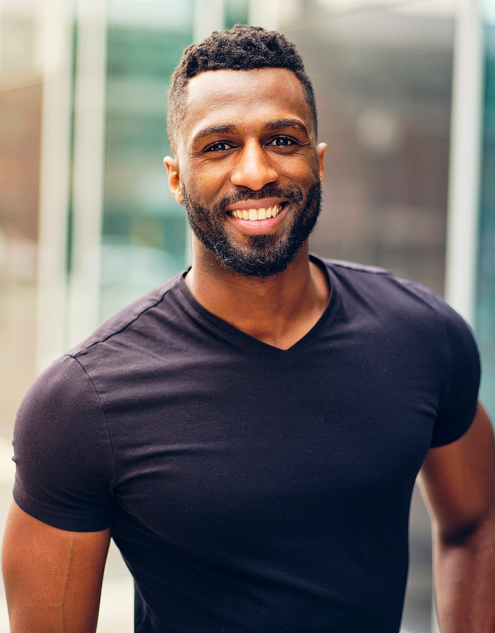 Smiling man in a black shirt outdoors.