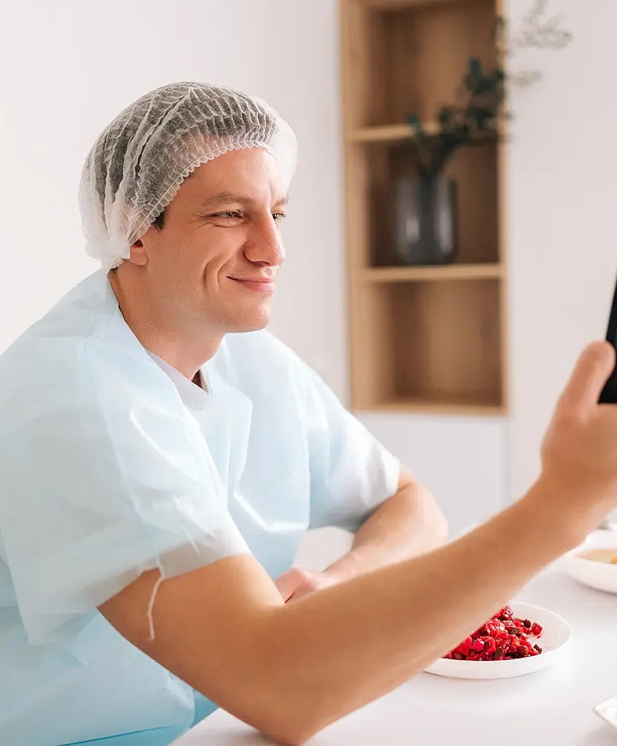 Man in hairnet smiling at phone.