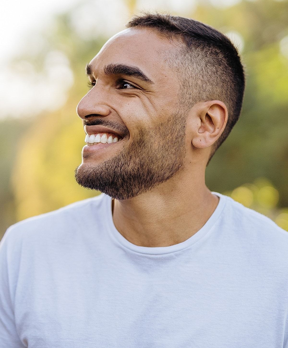 Smiling man wearing a white t-shirt outdoors.