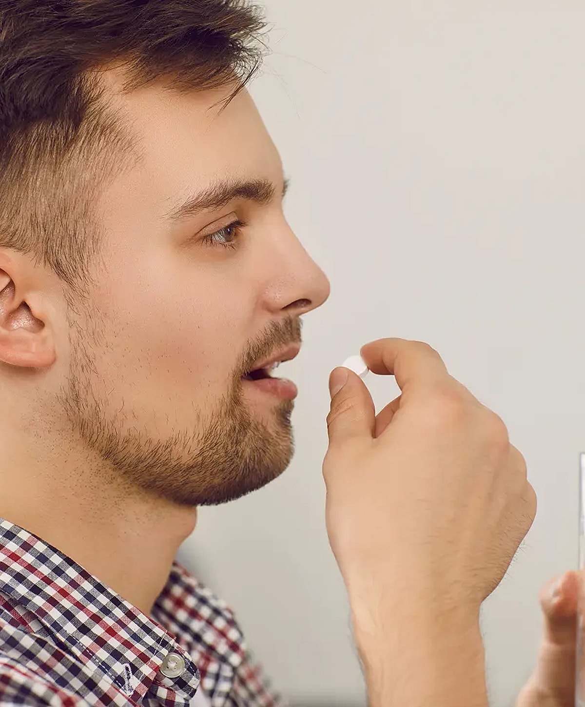 Man taking a pill with glass of water.