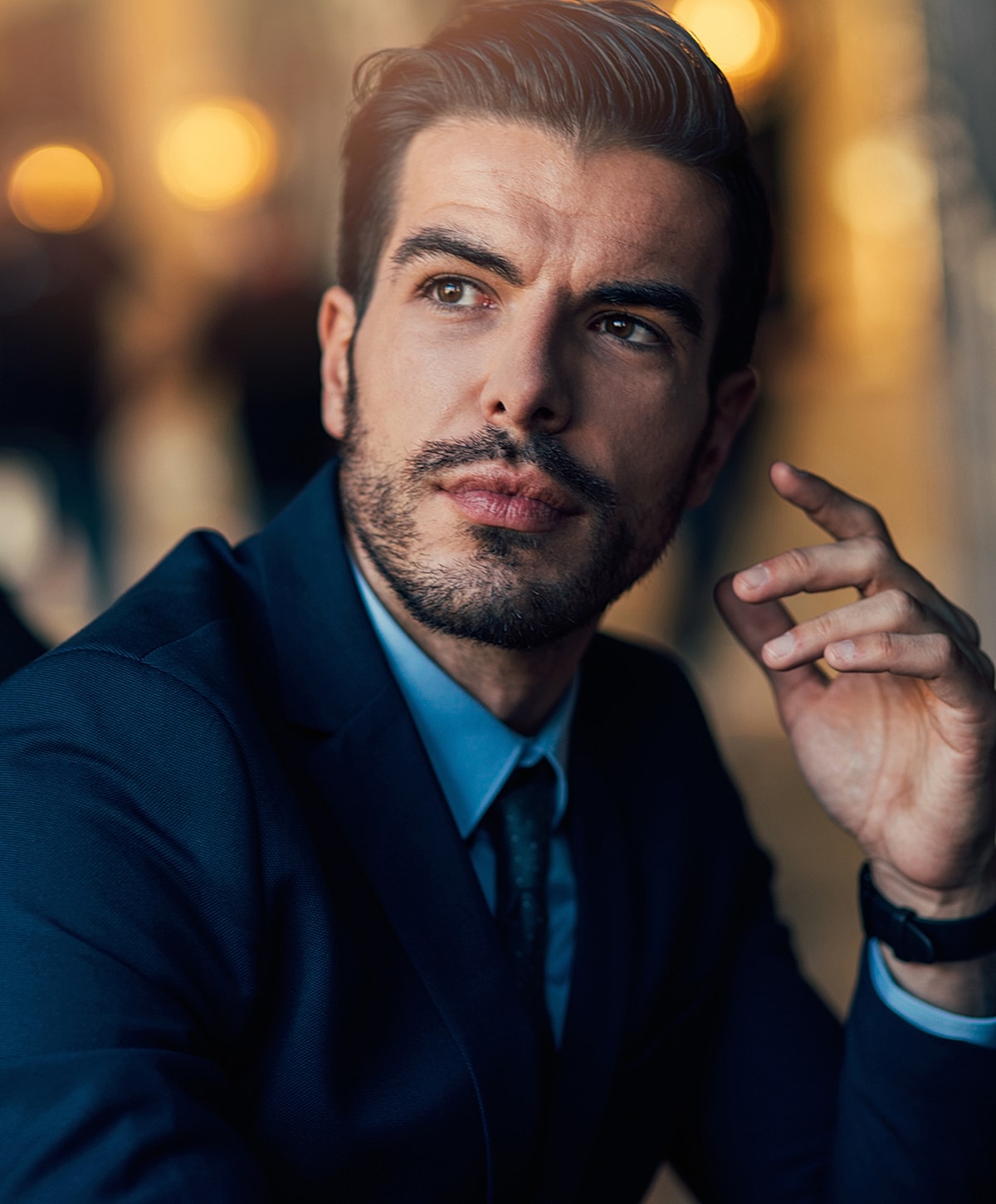 Man in suit contemplating thoughtfully indoors.