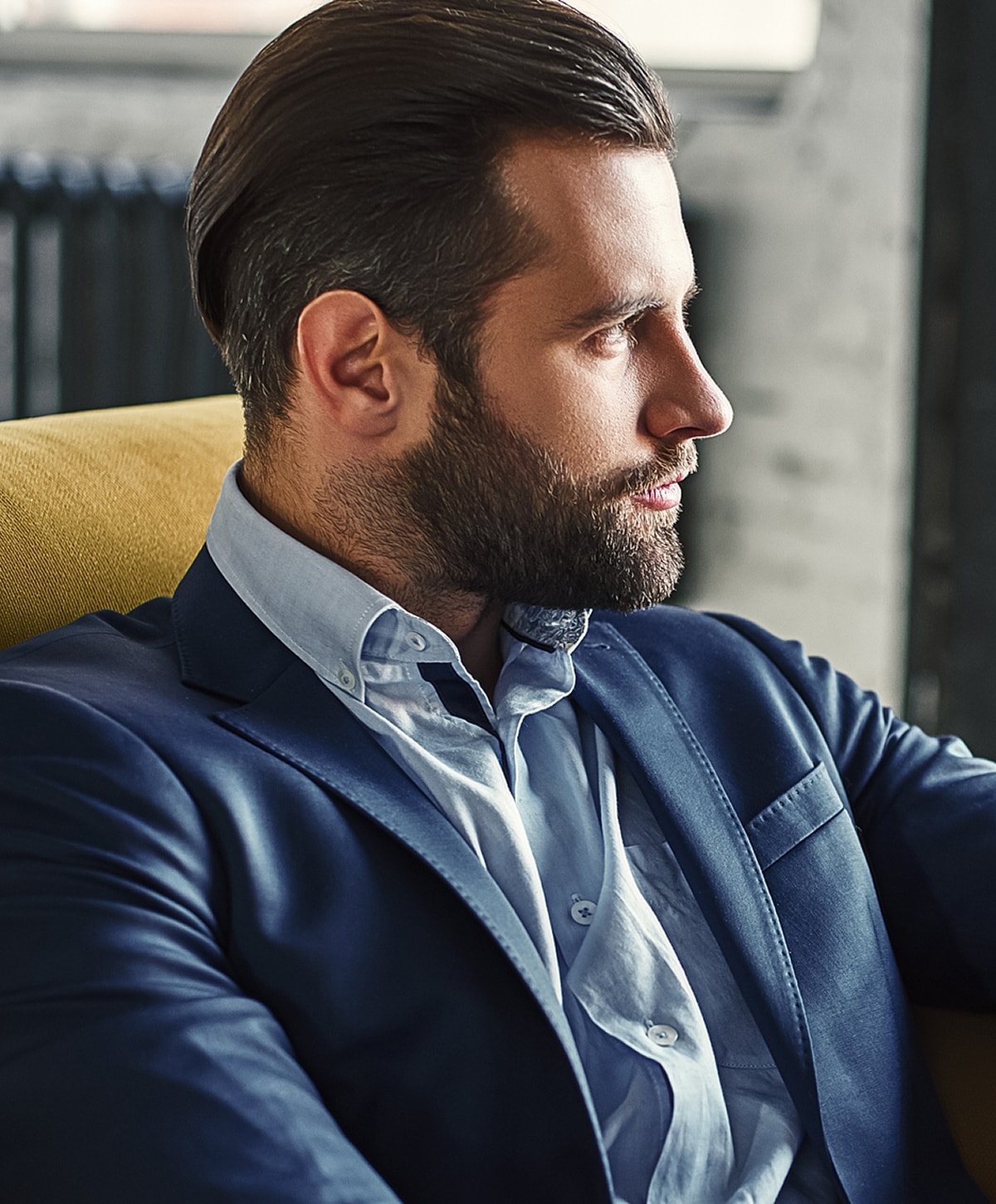Businessman in suit sitting thoughtfully on a couch.