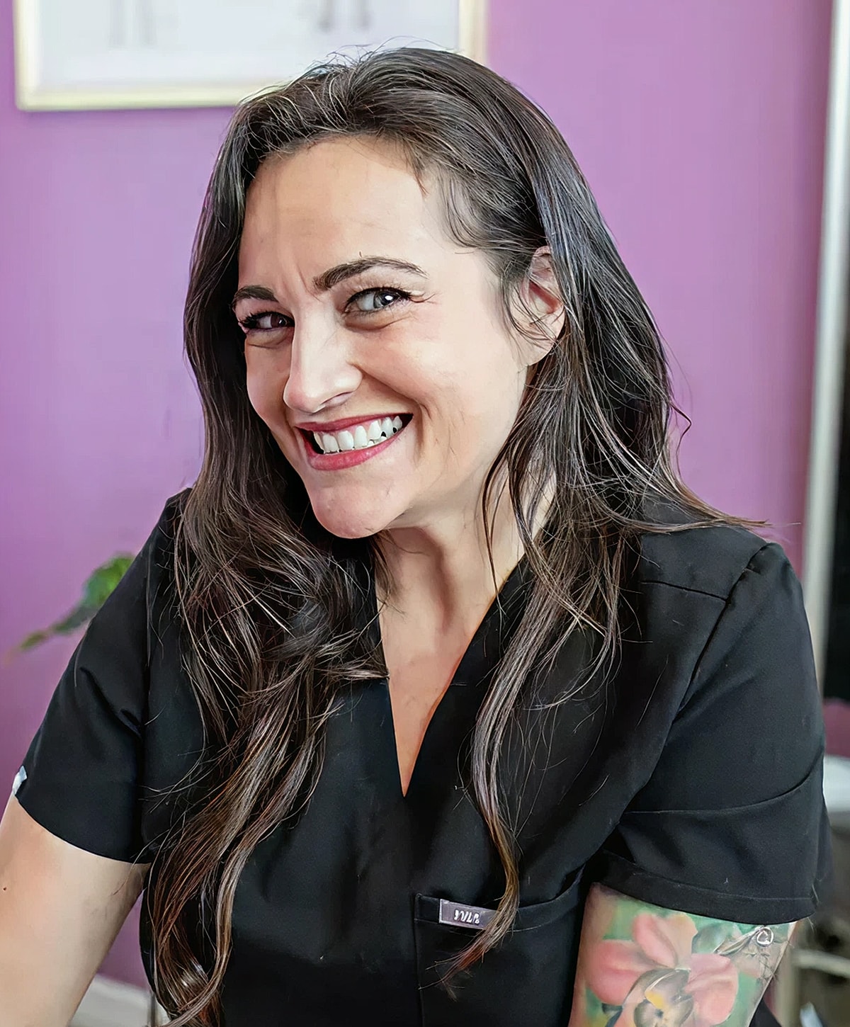 Smiling woman in professional attire against purple wall.