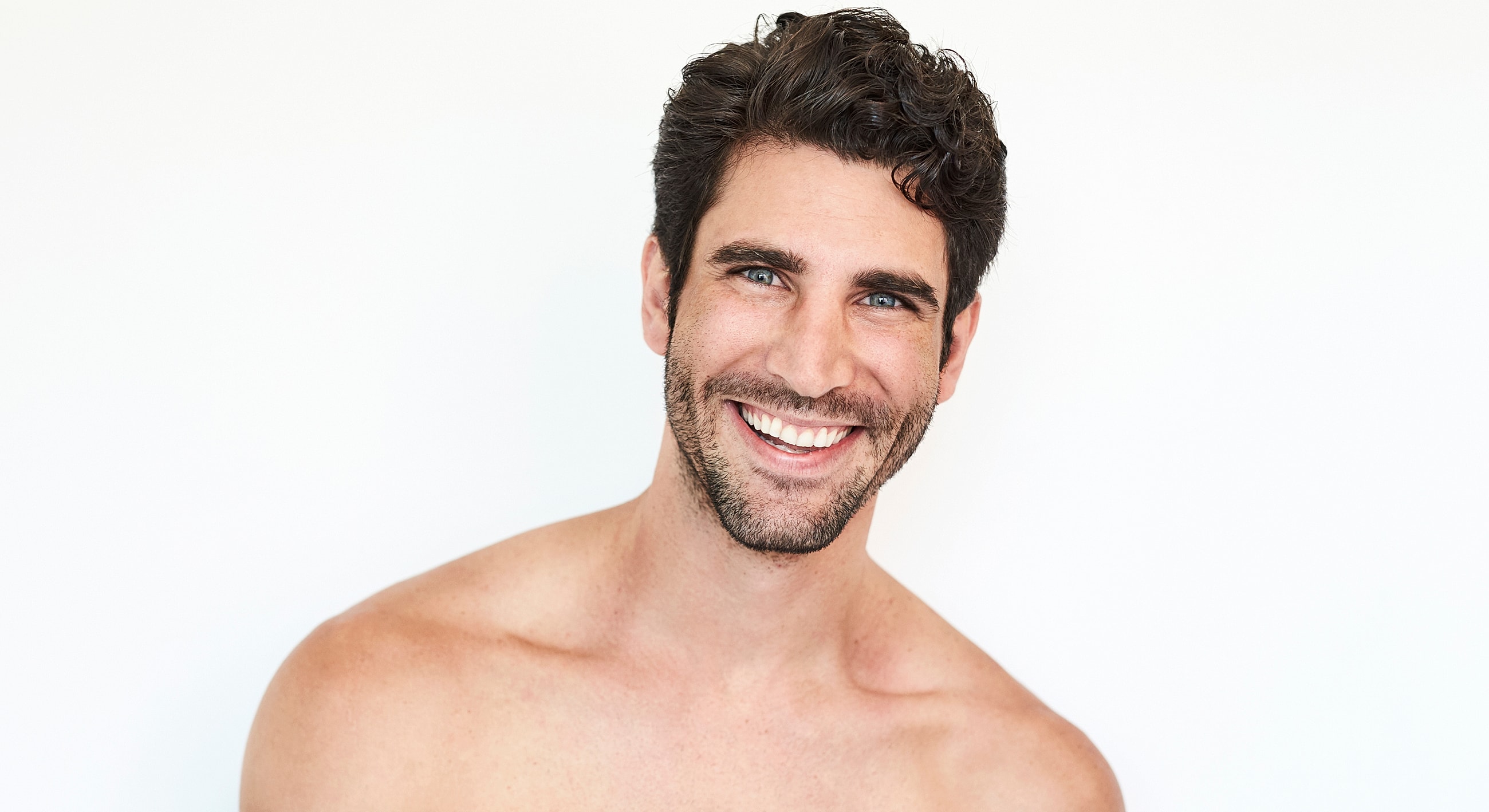 Smiling man with dark hair against white background.