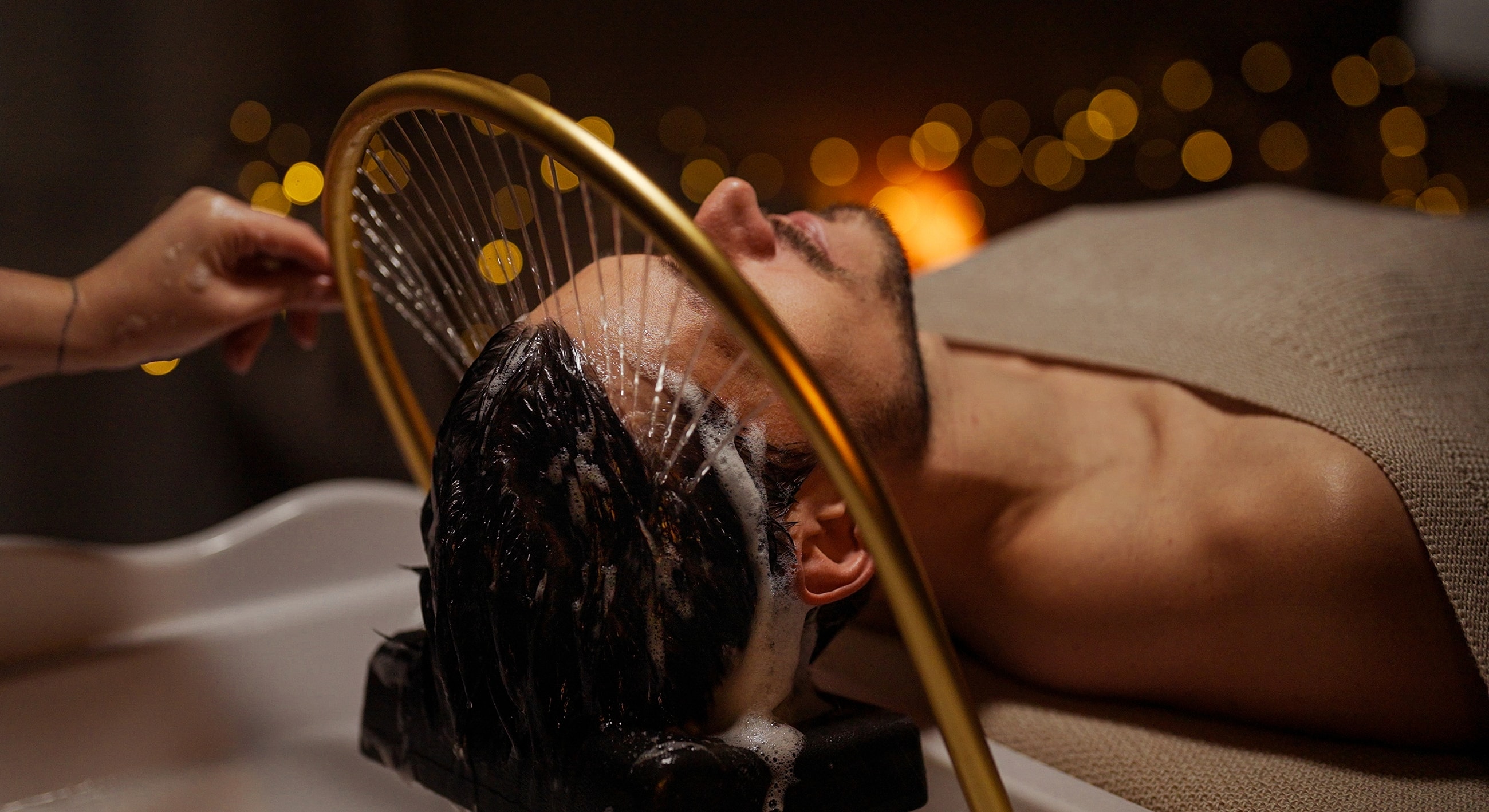 Person receiving a hair wash treatment at spa.