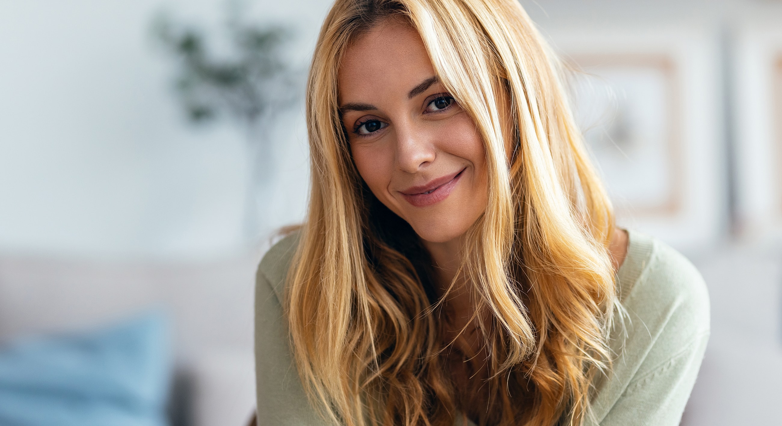 Smiling woman with long blonde hair indoors.