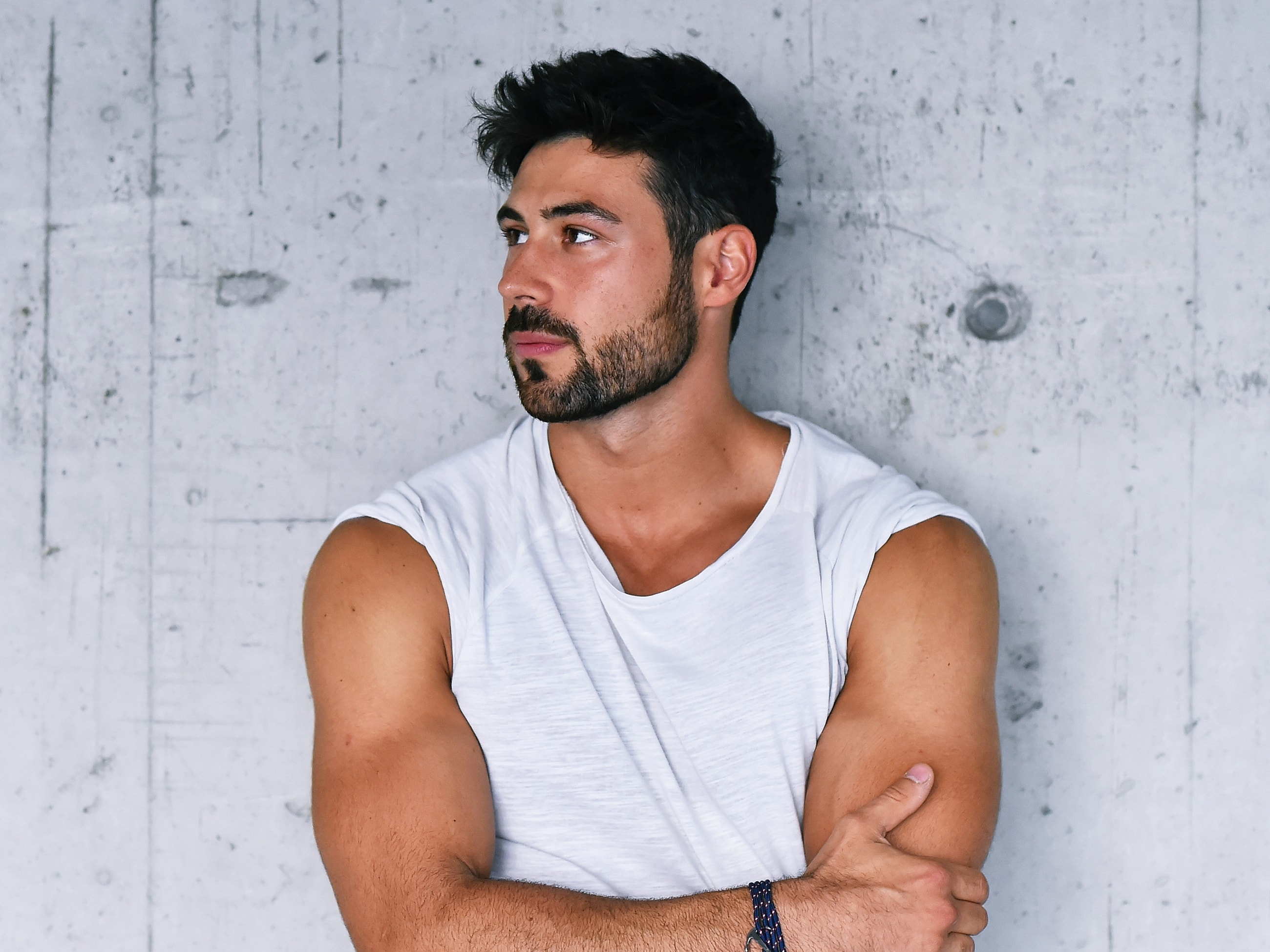 Man in white shirt leaning against concrete wall.