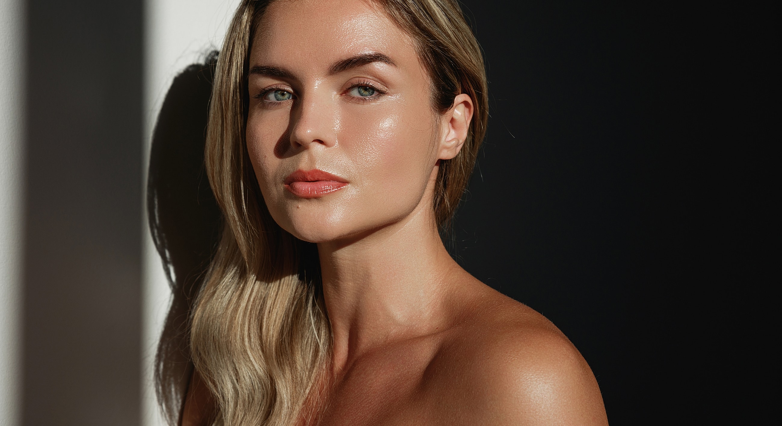 Woman with glowing skin in dramatic lighting.